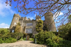 Malahide castle on a sunny day People sitting in front of Malahide Castle